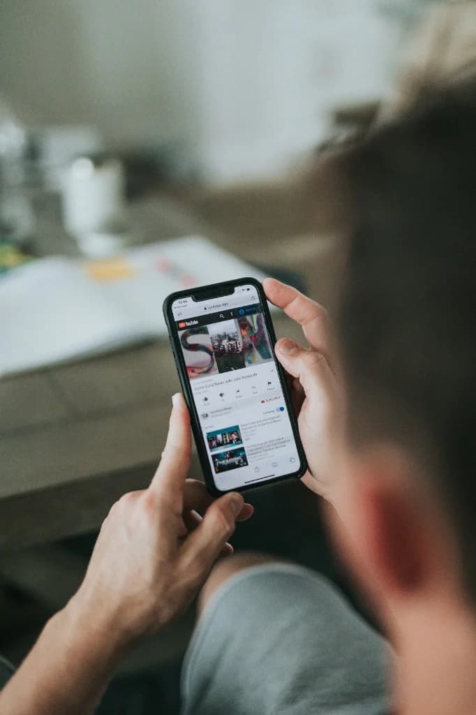 Personne assise, smartphone en main, écran avec vidéo en ligne — ce que le lien en vrai dépasse.