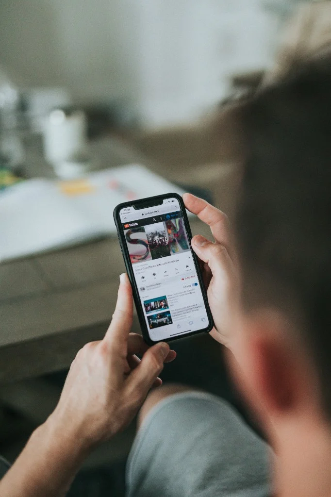 Person sitting with a smartphone, screen showing online video — what in-person connection goes beyond.